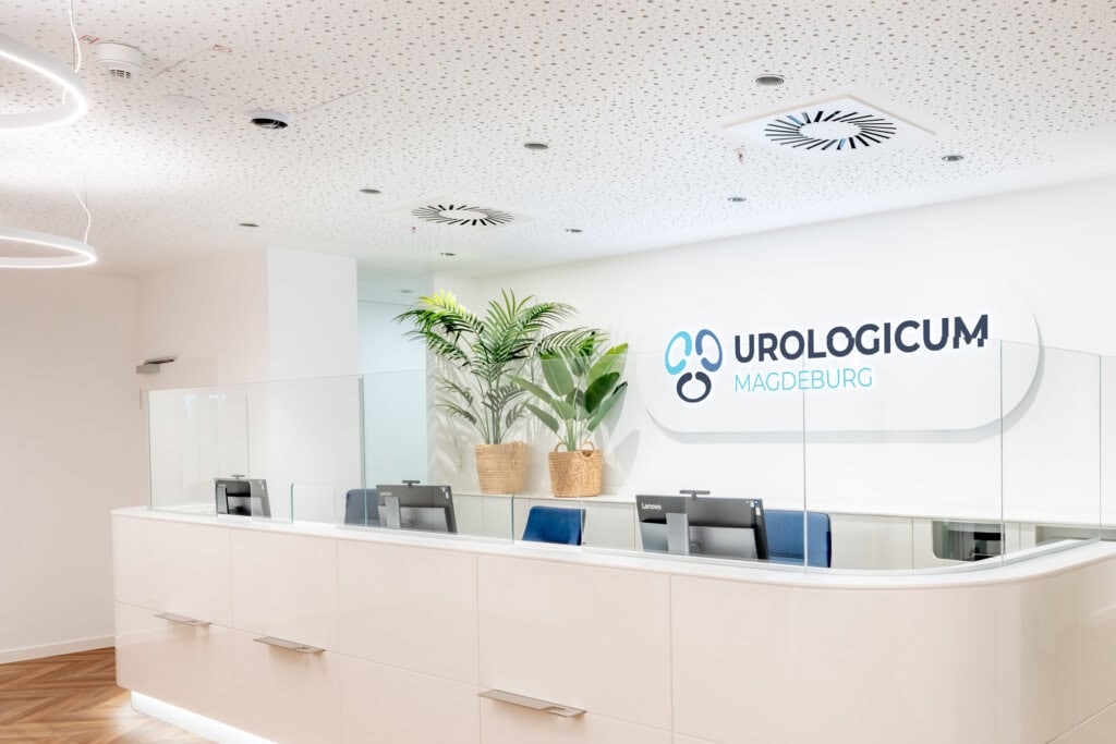 Der Eingangsbereich mit Logo-Schild und Empfangstresen vom Urologicum Magdebrug